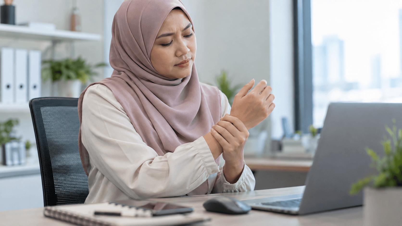 Pekerja pejabat memegang pergelangan tangan selepas menggunakan komputer